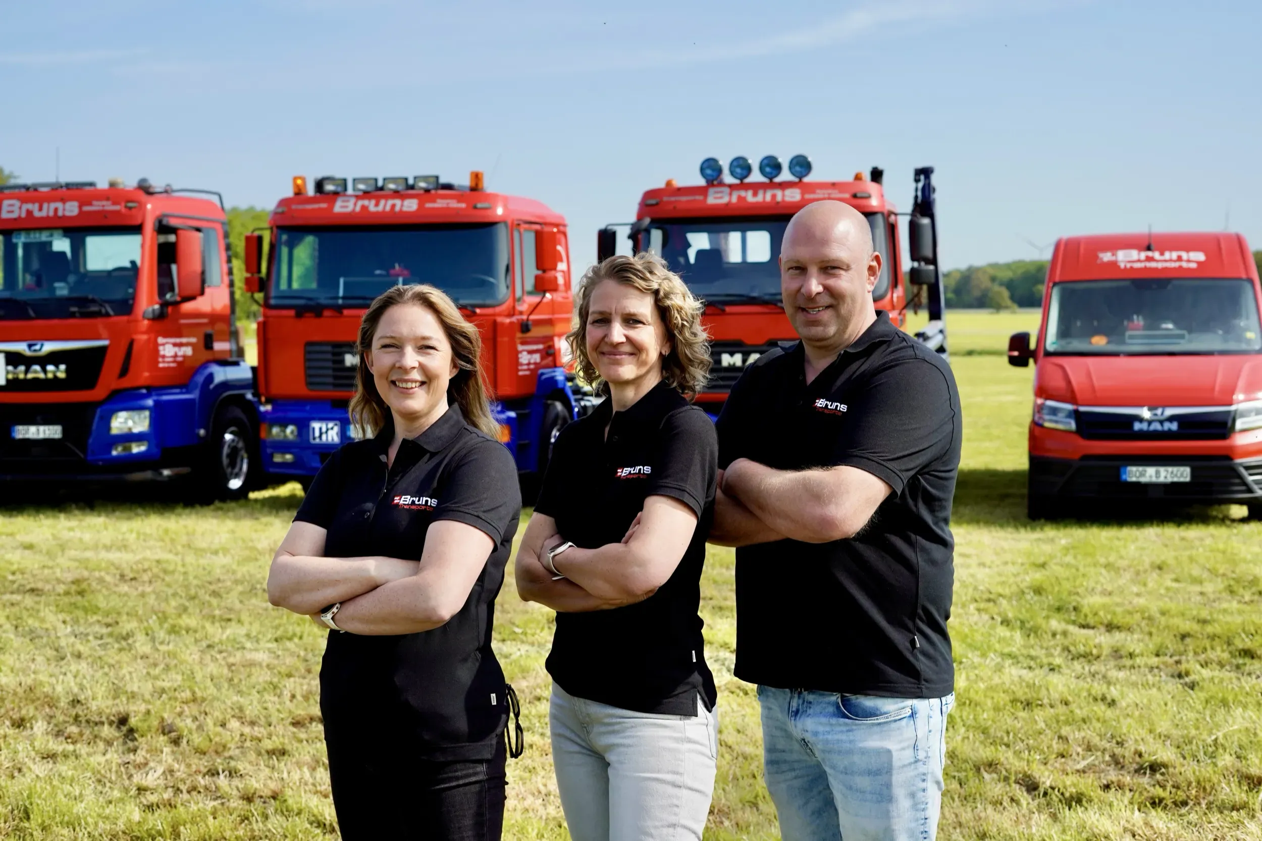 Drei Mitarbeitende von Bruns Transporte vor dem Fuhrpark